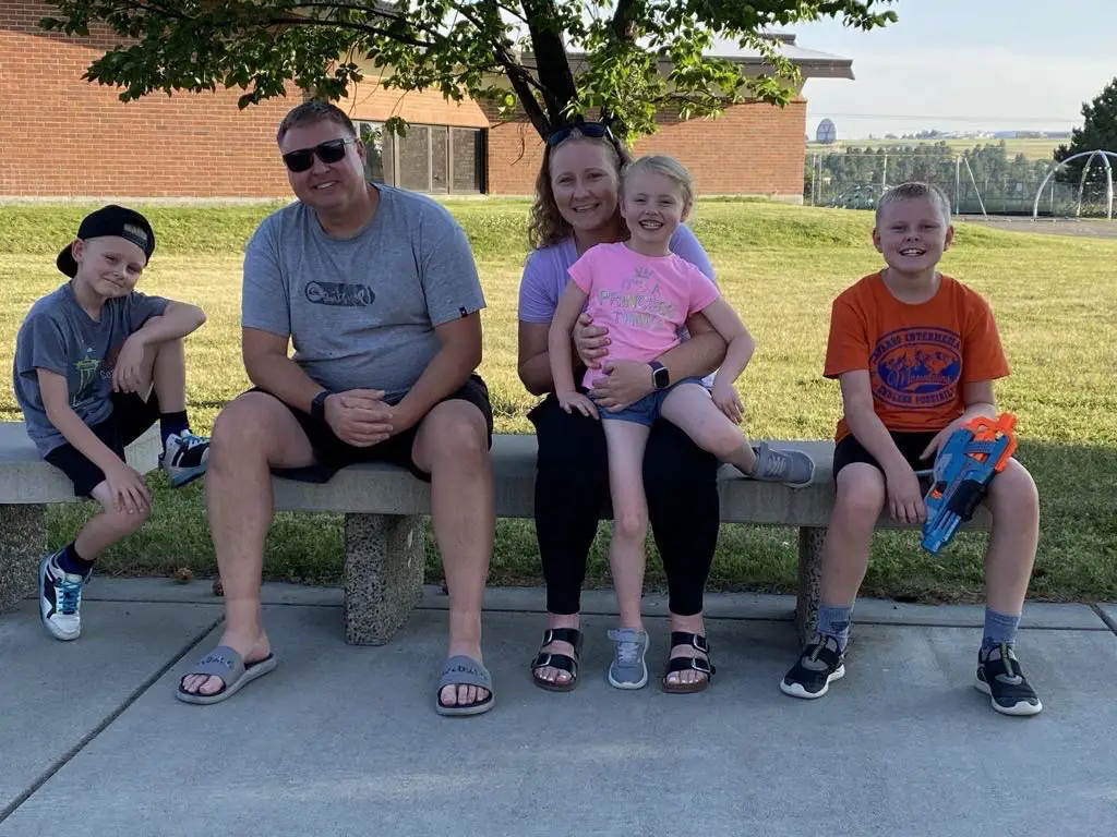 Shawn Sylvia of Veteran Air Warriors featured in a veteran spotlight, sitting on a park bench with his family, smiling and enjoying the outdoors.